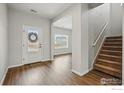 Inviting home entryway featuring hardwood floors, staircase, and natural light streaming through the front door at 2310 Angus St, Mead, CO 80542