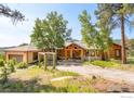 Charming single-story log cabin with stone accents, manicured trees, and a long private drive at 24043 Eagle Cliff Trl, Conifer, CO 80433