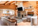 Open-concept living room featuring a stone fireplace, wood beams and vaulted ceilings at 24043 Eagle Cliff Trl, Conifer, CO 80433