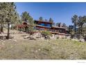 Beautiful wooden home with large windows, surrounded by rocks, trees and grassy landscape, ideal for nature lovers at 311 Sky Trail Rd, Boulder, CO 80302