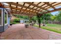 Spacious patio area with pergola, stone floor, and seating, surrounded by a well-maintained lawn and garden at 419 Centennial Dr, Louisville, CO 80027