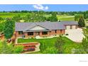 Aerial view of a brick home with well-kept landscaping, lush green lawns and detached garage at 612 Joyce Ct, Berthoud, CO 80513