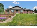 Charming single-story brick home with a well-manicured front yard and landscaped garden at 612 Joyce Ct, Berthoud, CO 80513