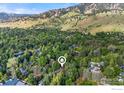Aerial view of a property nestled among lush trees and greenery with mountain backdrop at 701 Kalmia Ave, Boulder, CO 80304