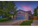 Well-maintained home featuring stone accents, a blue garage door, and mature trees at 10947 W 100Th Dr, Westminster, CO 80021