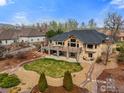 Expansive backyard featuring a large deck, a hot tub, a stone patio with fire pit, and mature trees at 13866 W 76Th Pl, Arvada, CO 80005