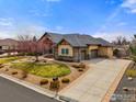 Attractive home with a three-car garage, stone accents, gabled roof, and well-manicured front lawn and landscape at 13866 W 76Th Pl, Arvada, CO 80005