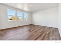Bright bedroom with three large windows and stylish wood-look flooring at 1671 Pinnacle Ave, Lochbuie, CO 80601