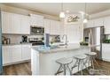 Modern kitchen with white cabinets, granite countertops, stainless steel appliances, and bar seating at 226 Chardon Ave, Brighton, CO 80601