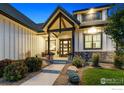 Inviting front porch with stone accents, a welcoming entrance, and professional landscaping at 2932 Heron Lakes Pkwy, Berthoud, CO 80513