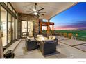An outdoor patio with a pergola, fire pit, stone wall and comfortable seating overlooking the golf course at 2932 Heron Lakes Pkwy, Berthoud, CO 80513