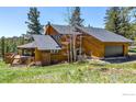 Exterior view of a rustic home featuring wood siding, a garage, and a deck, set in a natural landscape at 394 Deer Trail Cir, Boulder, CO 80302