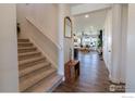 Bright home foyer featuring hardwood floors, staircase, and a view into the sunny living space at 4918 Preserve Pl, Firestone, CO 80504