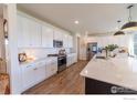 Modern kitchen boasts white cabinetry, stainless steel appliances, and a spacious quartz countertop island at 4918 Preserve Pl, Firestone, CO 80504