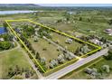 Aerial view of the property, defined by a yellow boundary, showcasing landscaping, pond, and mountain views at 5575 Saint Vrain Rd, Longmont, CO 80503