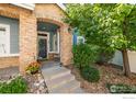 Inviting home entrance with stone accents, a cozy porch and mature landscaping at 64 Whitehaven Cir, Highlands Ranch, CO 80129
