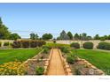 Backyard with manicured flower beds, lush green grass, and a white fence at 9629 Bountiful St, Firestone, CO 80504