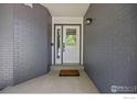 A welcoming front entrance with a decorative glass door and sidelight flanked by gray brick walls at 988 W Dahlia St, Louisville, CO 80027