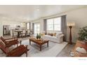 Bright living room open to dining area with hardwood floors and large windows for natural light at 1038 Scotts Peak Dr, Berthoud, CO 80513