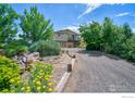 Two-story home with a well-maintained lawn, mature trees, and a gravel driveway at 13748 Downing St, Brighton, CO 80602