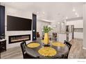 Open concept dining area with wood flooring, electric fireplace, and kitchen view at 173 Ambrose St, Erie, CO 80516