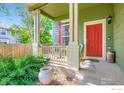 Inviting porch with a red front door, decorative columns, and space for seating, creating a welcoming entrance at 1747 Daisy Ct, Brighton, CO 80601