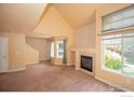 Bright living room with carpet, fireplace, and large windows for natural light; adjacent to staircase and front door at 805 Summer Hawk Dr # B7, Longmont, CO 80504