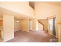 Open-concept living room with carpet, staircase, and view of kitchen area; features a neutral color palette at 805 Summer Hawk Dr # B7, Longmont, CO 80504