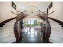 Grand foyer showcasing dual curved staircases, chandelier, and marble floors at 8337 Greenwood Dr, Niwot, CO 80503