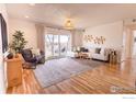 Bright living room featuring hardwood floors, neutral decor, balcony access, and an inviting, comfortable space at 12114 Melody Dr, Denver, CO 80234