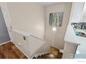 View of the hardwood staircase with a light wall color and an abstract painting at 1703 Whitehall Dr # G, Longmont, CO 80504