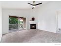 Bright living room featuring a cozy fireplace, ceiling fan, and sliding door access to a balcony at 3350 Boulder Cir # 201, Broomfield, CO 80023