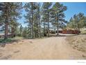Distant view of a home surrounded by dense trees, showcasing its private and secluded setting at 474 Leonards Rd, Boulder, CO 80302