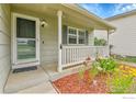 Inviting front porch featuring white railings, colorful flowers, and a storm door at 5493 Bobcat St, Frederick, CO 80504