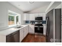 Bright eat-in kitchen with white cabinets, stainless steel appliances, and a stylish blue backsplash for a modern touch at 6019 S Pierson Ct, Littleton, CO 80127