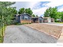 Charming single-story home featuring a brick facade, gravel landscaping, and long driveway at 8696 W 86Th Cir, Arvada, CO 80005