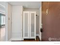 Entryway featuring a closet with glass doors, a wall-mounted cabinet, and wood flooring at 9995 E Harvard Ave, Denver, CO 80231