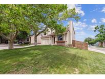 Well-maintained two-story home featuring a lush lawn, mature trees, and attached two-car garage at 693 Delwood Ct, Highlands Ranch, CO 80126