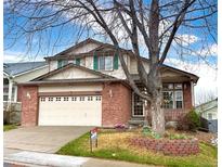 Charming two-story brick home with a well-manicured lawn and a large shade tree in the front yard at 13661 Adams St, Thornton, CO 80602