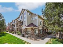 Attractive multi-story townhome featuring stone accents and well-maintained landscaping under a blue sky at 12711 Colorado Blvd # 1009, Thornton, CO 80241