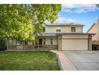 Charming two-story home with a covered front porch, brick accents, manicured lawn, and a two-car garage at 11978 W Aqueduct Dr, Littleton, CO 80127