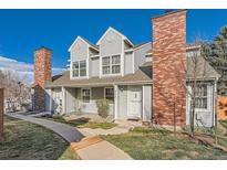 Charming townhome with gray siding, brick chimney, manicured lawn, and inviting front entrance at 8391 W 90Th Pl, Westminster, CO 80021
