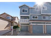 Inviting blue home featuring an attached garage and a charming second-story balcony at 10470 W 83Rd Ave, Arvada, CO 80005