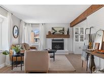 Cozy living room with a brick fireplace, light wood floors, and bright, natural light at 10810 W Alamo Pl, Littleton, CO 80127