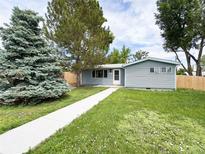 Charming single story home with manicured lawn and mature trees on a sunny day at 10025 W 8Th Ave, Lakewood, CO 80215