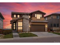 Beautiful two-story home with a two car garage, stone accents, manicured lawn and colorful sunset sky at 14710 Domino Dr, Parker, CO 80134