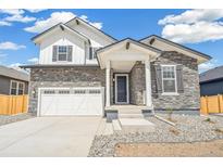 Charming two-story home featuring stone accents, white trim, a two-car garage, and professional landscaping at 6207 E 155Th Pl, Brighton, CO 80602
