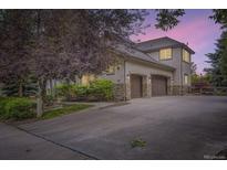 Exterior view of a stucco home featuring a large driveway and a two-car garage with stone accents at 714 Skywalker Pt, Lafayette, CO 80026