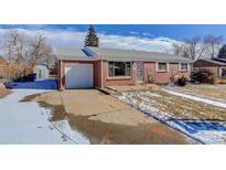 Charming single-story brick home featuring a driveway, attached garage, and partially snow-covered front yard at 4755 S Irving St, Englewood, CO 80110