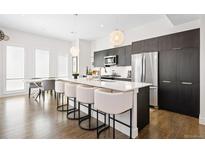 Modern kitchen boasts stainless steel appliances, quartz countertops, and large island with seating at 4395 Zuni St, Denver, CO 80211